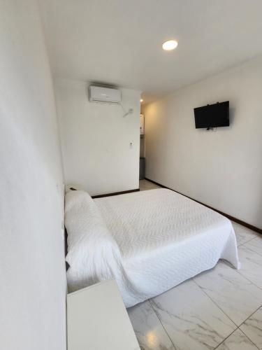 1 dormitorio con 1 cama blanca y TV en la pared en SONSOLES HOTEL en Paso de la Patria