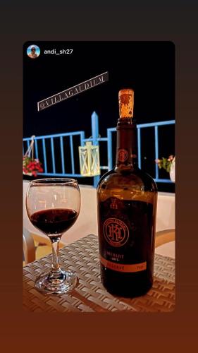 a bottle of wine next to a glass of wine at Villa Gaudium in Vlorë