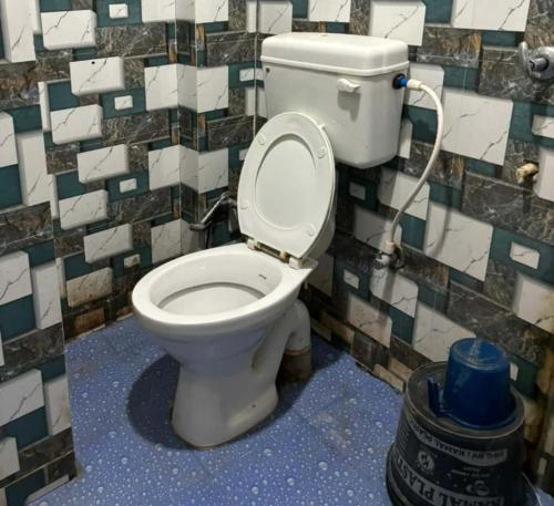 a toilet in a bathroom with a tiled wall at GRG Sunrise Plaza Deoghar in Deoghar