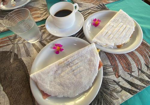 a table with two plates with sandwiches and a cup of coffee at Pousada Cantinho do Sossego in Arraial d'Ajuda