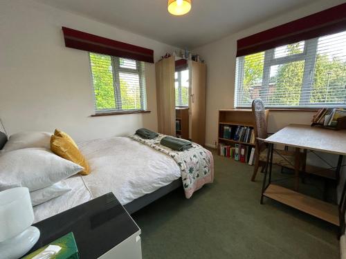 1 Schlafzimmer mit einem Bett, einem Schreibtisch und 2 Fenstern in der Unterkunft Wimbledon village and tennis in London