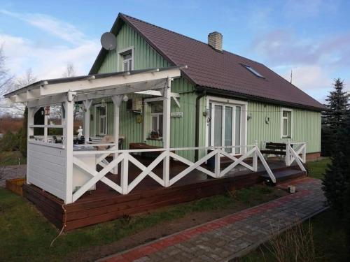 a green house with a white roof and a porch at Rähni Guesthouse Lake Peipsi in Vilusi
