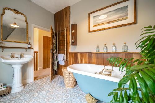 a bathroom with a bath tub and a sink at Samphire Cottage by Big Skies Cottages in Docking
