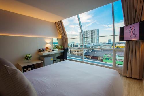 a hotel room with a large bed and a large window at Crystal Hotel Hat Yai in Hat Yai