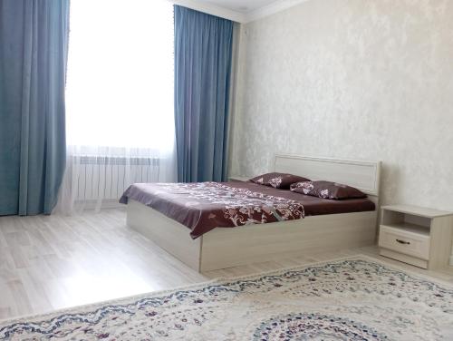a bedroom with a bed and a large window at ЖК Арай in Aktobe