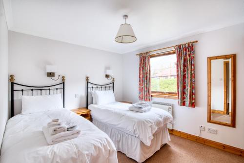 two beds in a room with a mirror and a window at Kingfisher Lodge sleeps up to 4 in Crianlarich