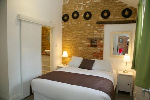 um quarto com uma cama grande e uma parede de tijolos em Mouse House at Tove Valley Cottages em Towcester