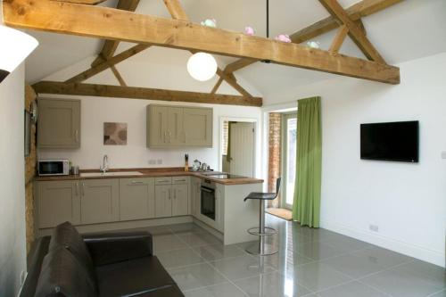 a kitchen with white cabinets and a television in a room at Mouse House at Tove Valley Cottages in Towcester