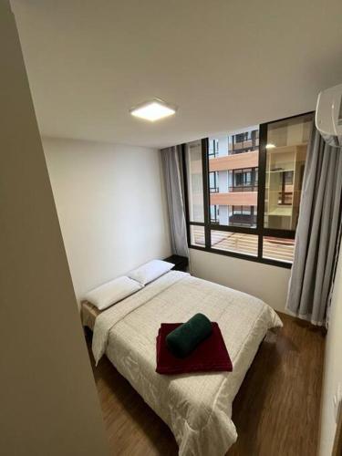 a bedroom with a bed with a red pillow on it at Apartamento 1 quarto, com garagem no centro próximo Hospital de Caridade in Santa Maria
