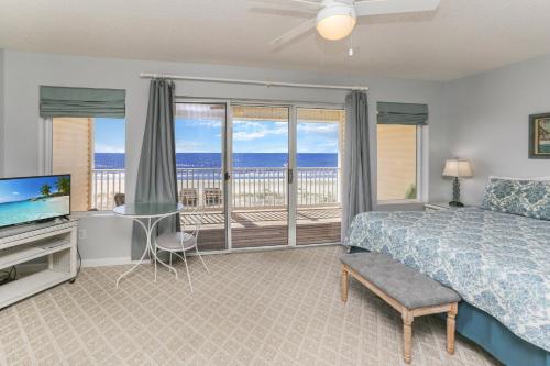 a bedroom with a bed and a television and a balcony at Pelican Landing 2 in Indian Pass