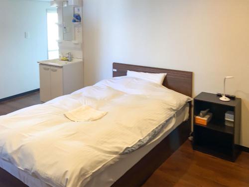 a bedroom with a large white bed with a night stand at Nomura Building Parkside - Vacation STAY 34551v in Fuji