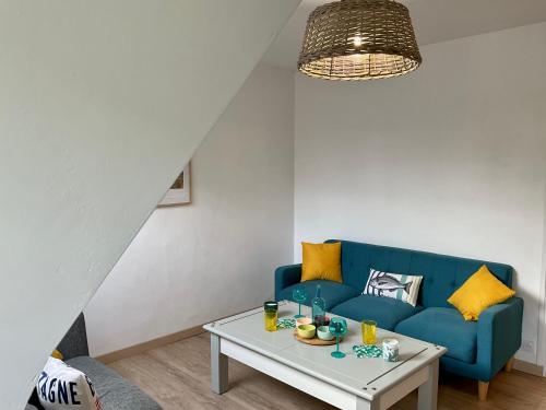 un salon avec un canapé bleu et une table dans l'établissement Appart T4 spacieux & lumineux proche de la mer, à Guidel