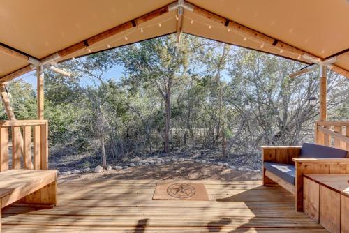 a wooden porch with benches and a view of the woods at Tent#1-Luxury Camping Tent in Hill Country, Texas in Johnson City