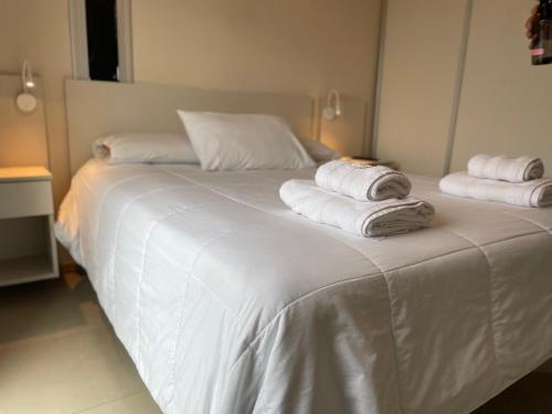 a white bed with towels on top of it at Departamentos Leloir in Neuquén