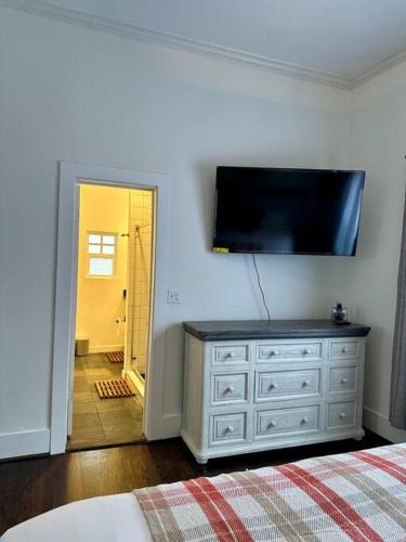 a bedroom with a dresser with a television on the wall at The Red Haven -Heart of EaDo HTX & NRG- in Houston