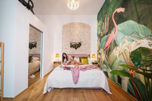 a woman sitting on a bed in a room with a mural at Casa Apuliae Bed & breakfast in Bitonto