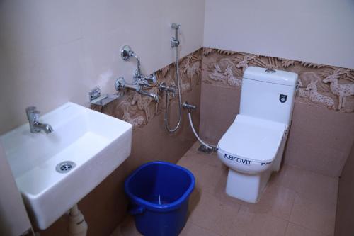 a bathroom with a white toilet and a sink at Heaven Resorts in Yercaud