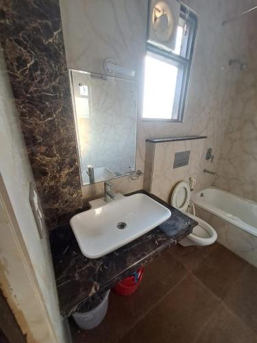 ein Badezimmer mit einem Waschbecken, einem WC und einem Spiegel in der Unterkunft F2B stay in Mathura