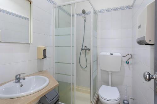 a bathroom with a shower and a toilet and a sink at Le Penguin Hostel in Faro