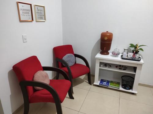 a room with two red chairs and a table at Quarto confortável em Est Velha in Genuino Sampaio