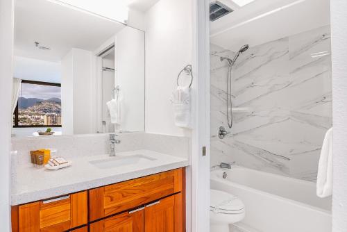 La salle de bains blanche est pourvue d'un lavabo et d'une douche. dans l'établissement Beautiful Renovated Mountain View Condo with Parking!, à Honolulu
