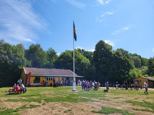 a group of people standing around a building with a flag pole at Ormanäsgårdens Stugby in Höör