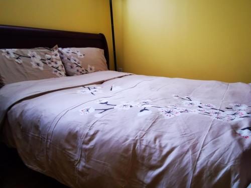 Una cama con sábanas blancas con flores. en one queen-sized bed convenient location en Toronto
