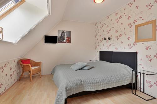 1 dormitorio con 1 cama con flores rosas en la pared en Bron van Rust en Siegerswoude