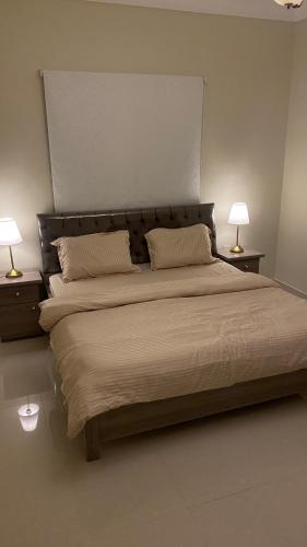 a bedroom with a large bed with two lamps at شقه بصالة انيقة وغرفة نوم . in Al Khobar