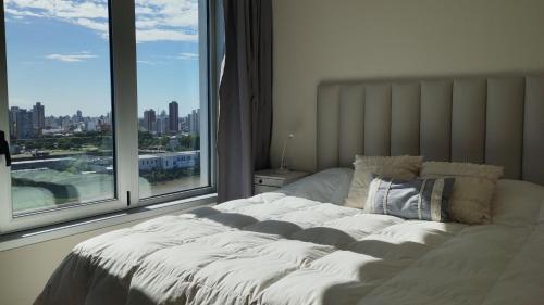 a bed in a bedroom with a large window at Impactante vista al Río, moderno y con cochera! in Santa Fe
