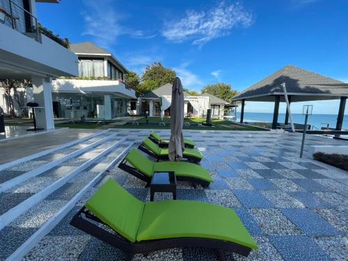 a row of green lounge chairs and an umbrella at Bluemango Pool Villa & Resort Koh Samui in Koh Samui 