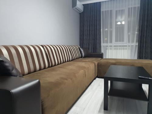 a living room with a brown couch and a table at Батыс LUX in Aktobe