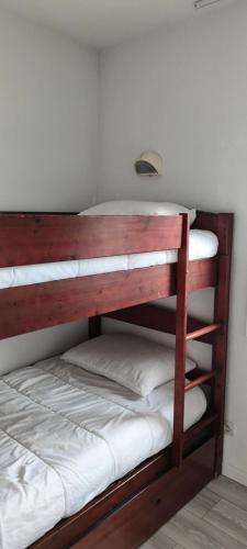 Ce lit superposé en bois se trouve dans un dortoir. dans l'établissement Les maisons de Port Guillaume - maeva Home - Maison 3 Pièces 6 Personnes Sélection MAE-2279, à Dives-sur-Mer