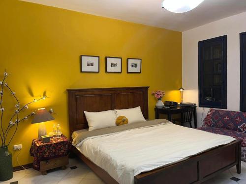 ein Schlafzimmer mit einem Bett und einer gelben Wand in der Unterkunft GÁC home & decor in Hanoi