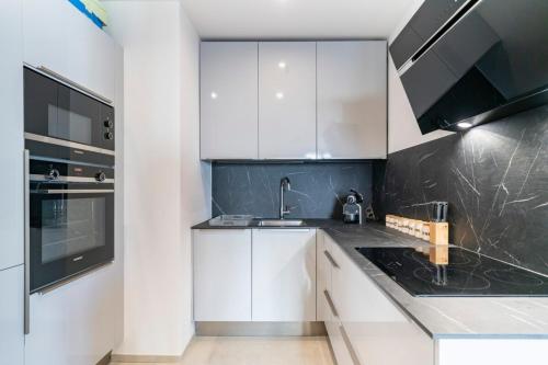 une cuisine avec des armoires blanches et des appareils noirs dans l'établissement Very nice 3 bedrooms apartment in the heart of downtown Cannes, à Cannes