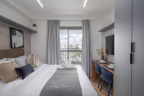 a bedroom with a bed and a desk and a window at 360 My Moema in São Paulo