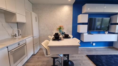 een keuken met witte kasten en een blauwe muur bij BLUE APARTMENT in Polanica-Zdrój