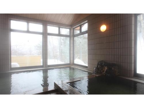 um quarto com uma piscina de água com janelas em Nakanoyu Onsen Ryokan - Vacation STAY 06683v em Matsumoto