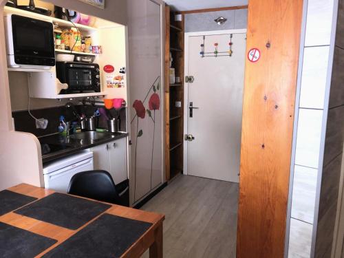 eine kleine Küche mit einem Tisch und einer Tür in der Unterkunft Résidence quartier Hauts-Forts - Maeva Particuliers - Studio 4 Personnes Confort - Le Pas du Lac 124223 in Morzine