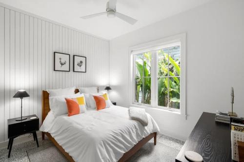 a bedroom with a white bed with orange pillows and a window at Casa Cohiba - Ybor City Townhouse in Tampa