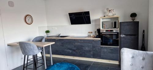 cocina con nevera negra, mesa y sillas en LE COTTAGE en Séné