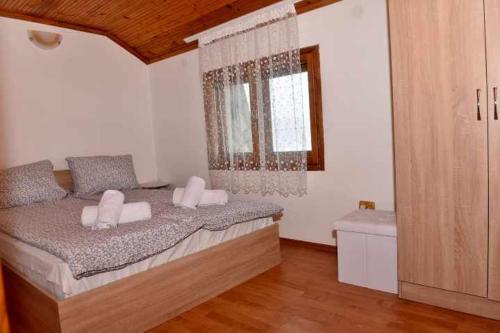 um quarto com uma cama com almofadas brancas e uma janela em Къща за гости Ленови em Elena