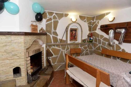 Una habitación con chimenea y una cama en una habitación en Къща за гости Ленови, en Elena