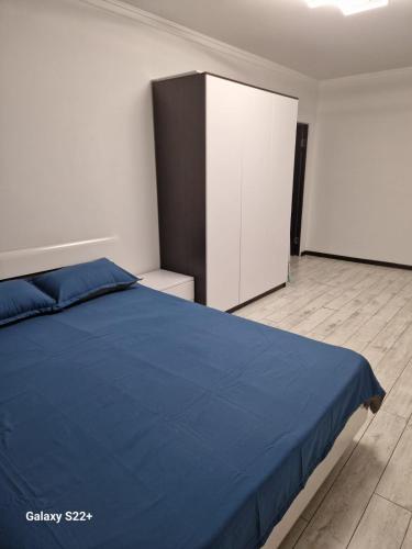 um quarto com uma cama azul e um armário em ЖК Актобе Ажары em Aqtöbe