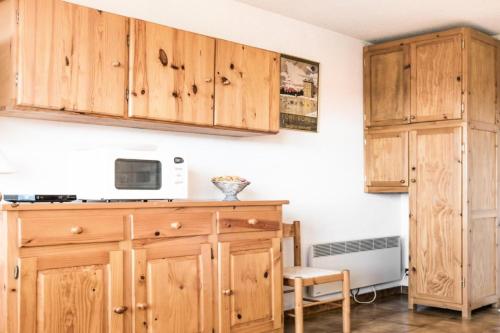 - une cuisine avec des placards en bois et un four micro-ondes dans l'établissement Studio 4 pers coeur de station - maeva Home - Studio 4 Personnes Confort MAE-7426, à Font-Romeu-Odeillo-Via