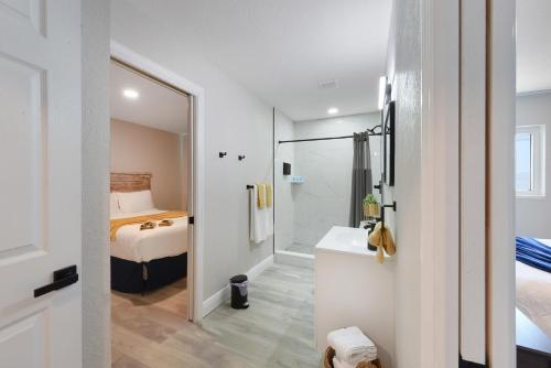 a bathroom with a sink and a shower and a bed at Palm Cove Motel in Clearwater