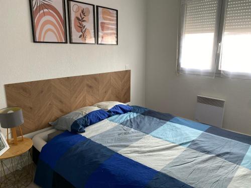 une chambre avec un lit avec une couette bleue et blanche dans l'établissement Appartement cosy agde, à Agde