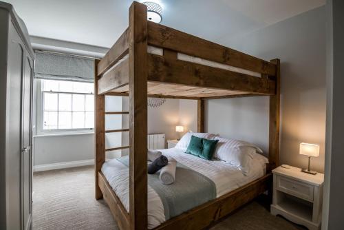 um quarto com um beliche de madeira com um urso de peluche em Lady Tenby - 2 Bedroom Apartment - Tenby (Windsor House) em Tenby