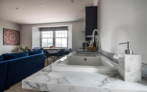uma cozinha com um grande lavatório branco e cadeiras azuis em Lady Tenby - 2 Bedroom Apartment - Tenby (Windsor House) em Tenby