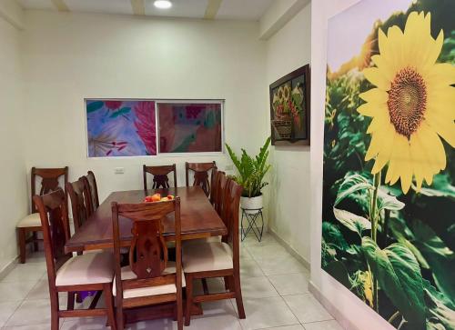 a dining room with a table and a sunflower painting at Hostal Doña Nancy in Mompos